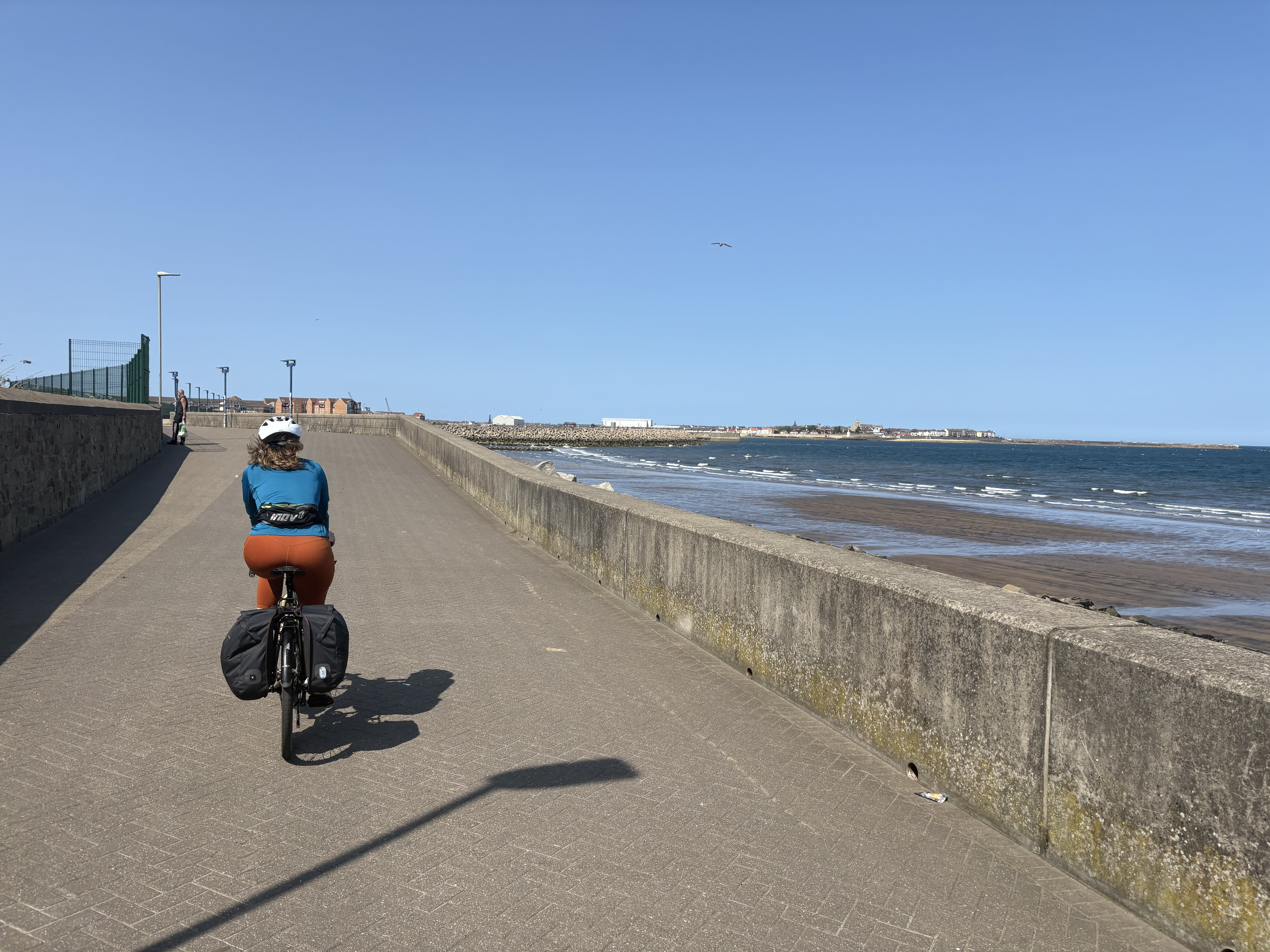 Following a cyclist along a promenade, with the sea on the right and the tide way out