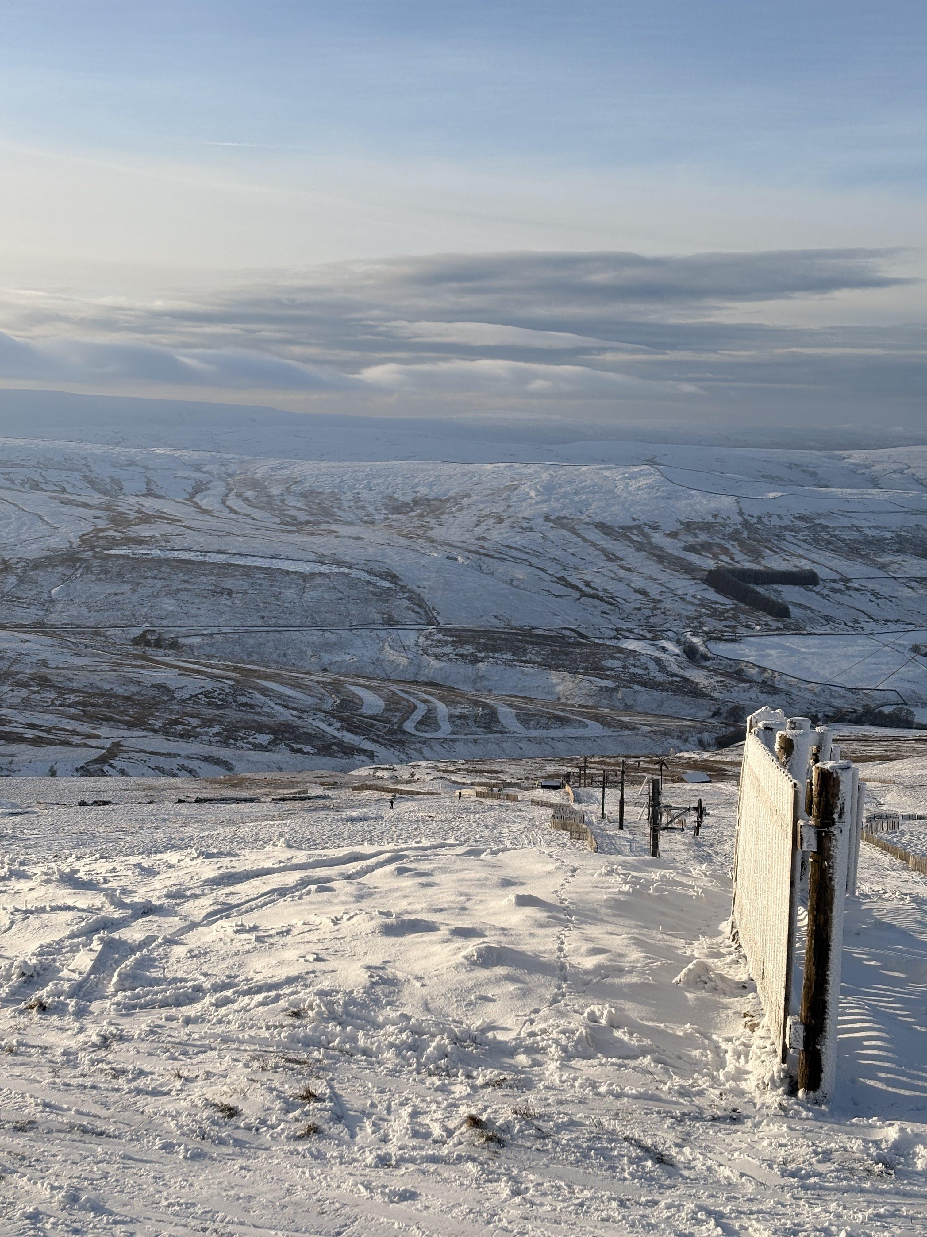A broken fenceline marks the boundaries of the Yad Moss ski field, with patchy snow on the slopes below and on the rolling hills climbing the other side of the dale