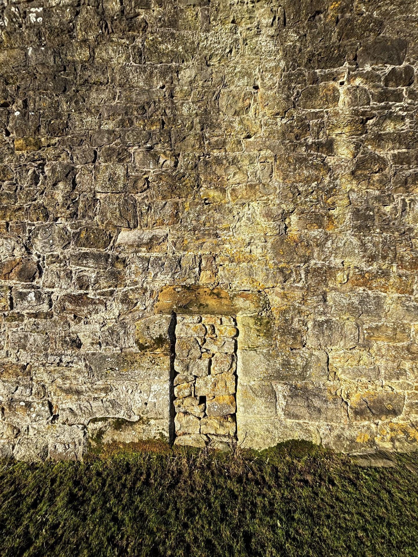 A tiny, blocked up doorway in a massive stone wall