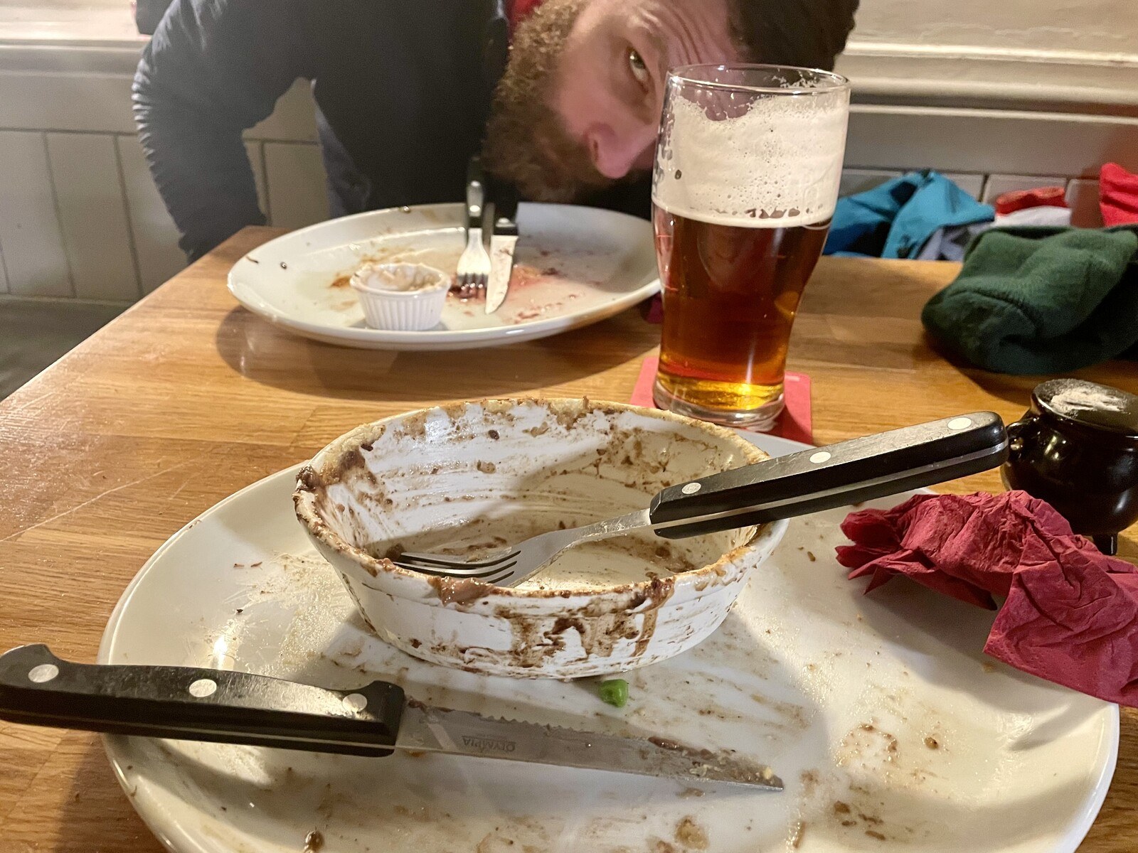 A pair of empty plates and a half-finished pint, me bent over to fit into the picture frame