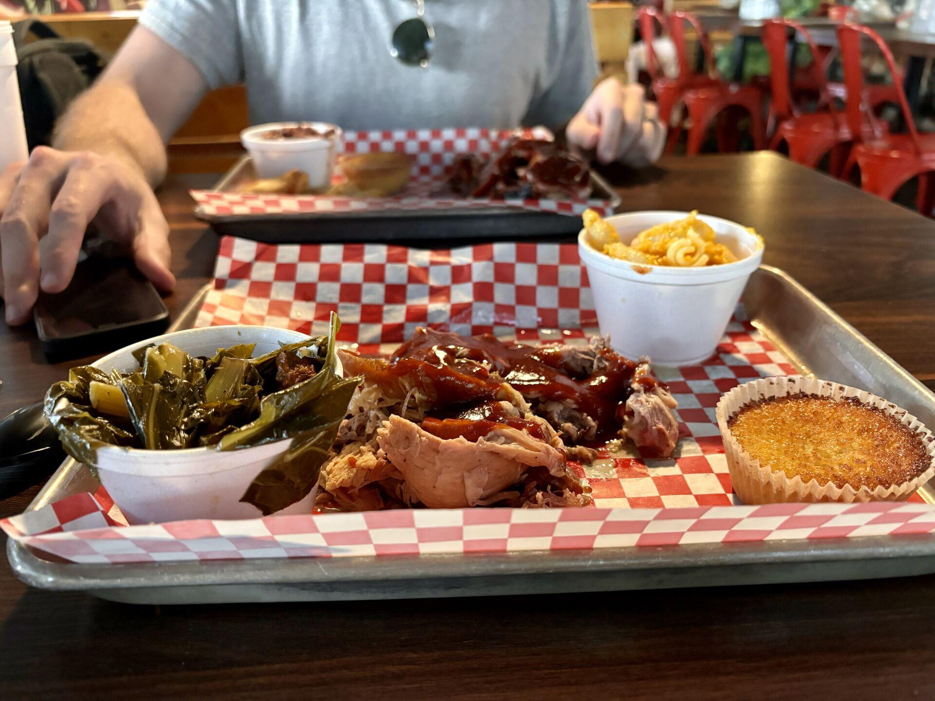 Two platters of barbeque at Daddy D'z in Atlanta, with sides of collard greens, mac & cheese, and red beans & rice