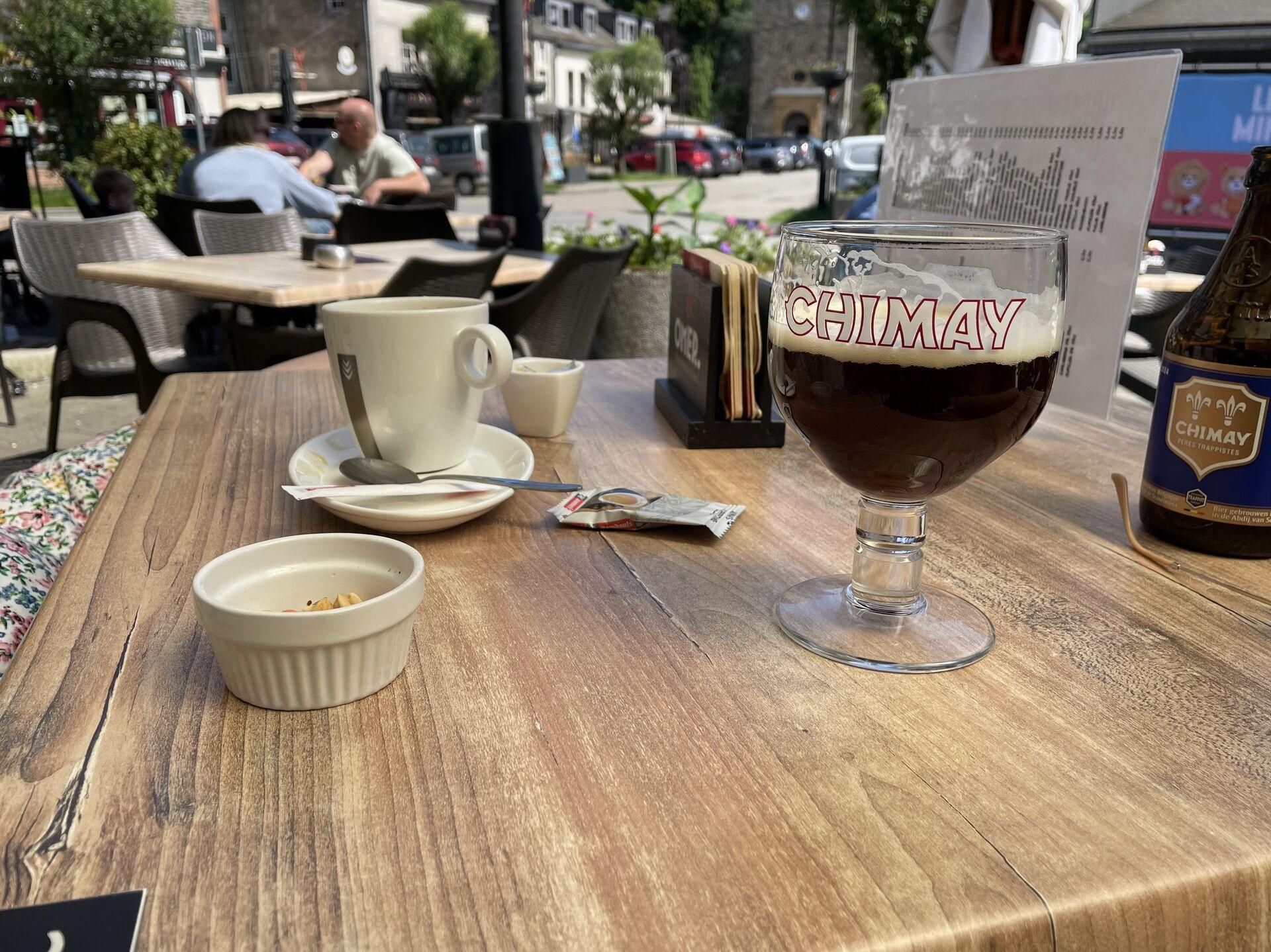 A half-finished glass of Chimay with a grande cafe and a little terrine of nuts at a cafe on the sidewalk in Bohan-sur-Semois