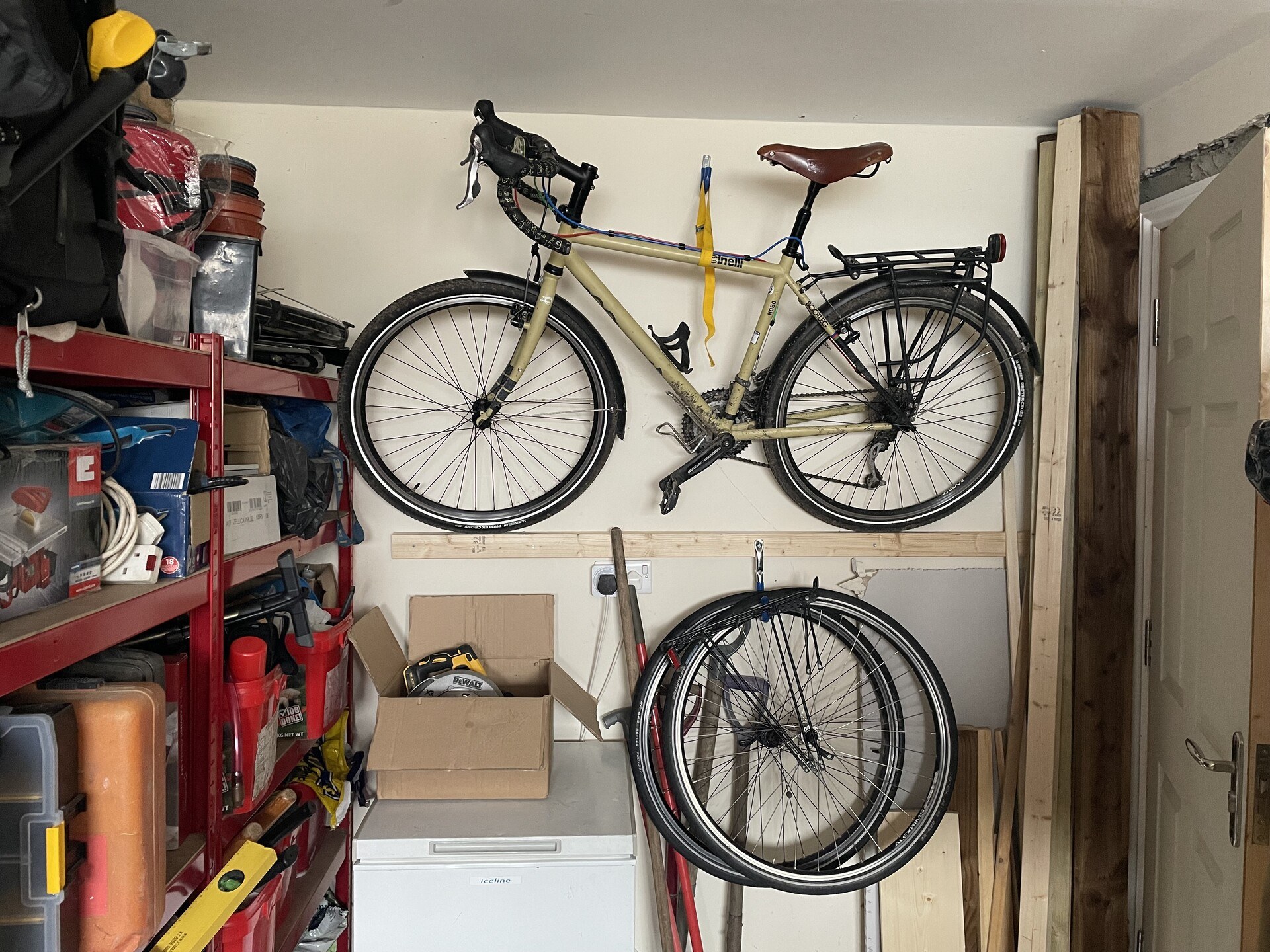 A bike mounted on the wall with a wooden rail and a strap to hold it upright.