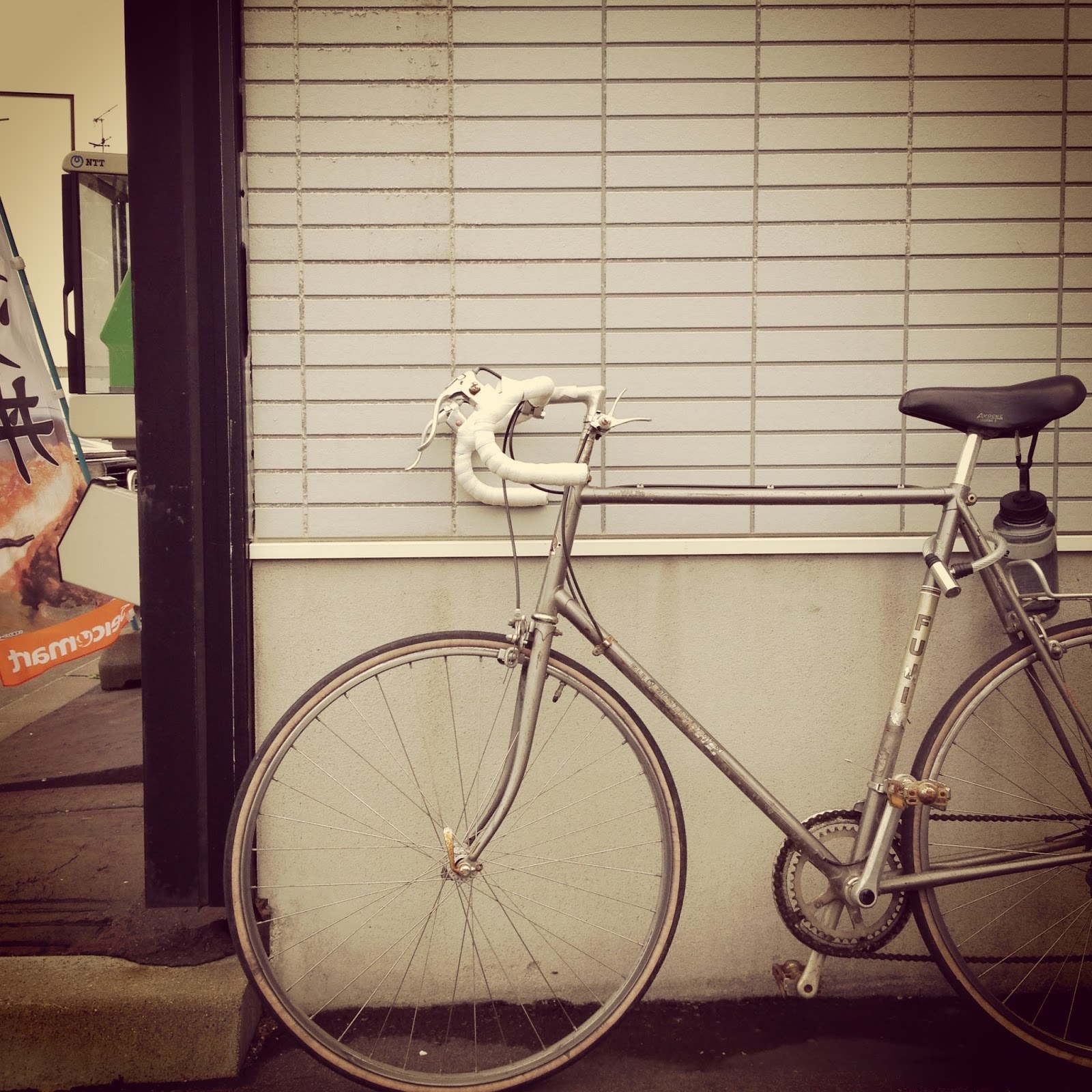 A cropped shot of my bike, a Fuji Espree from the 80s, leaning up against the side of a Seicomart