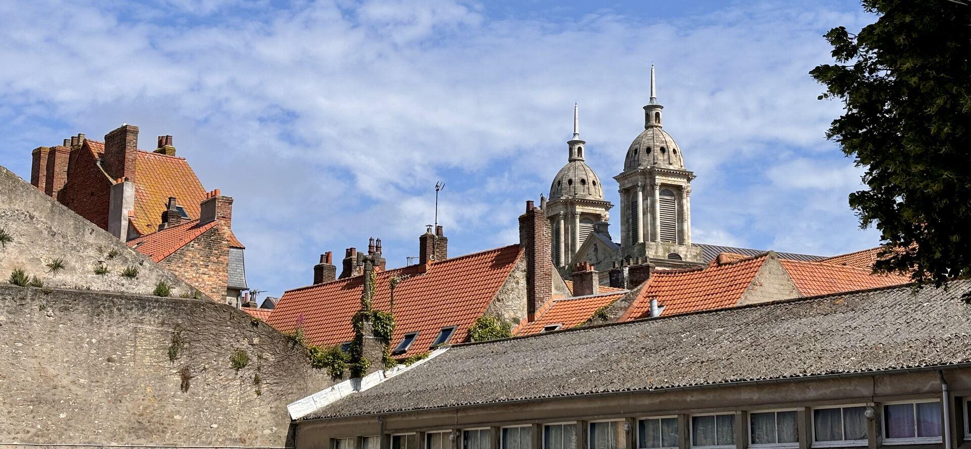 The stone and tile skyline of Boulogne from street level, a pair of church cupolas poking up above the orange tilery