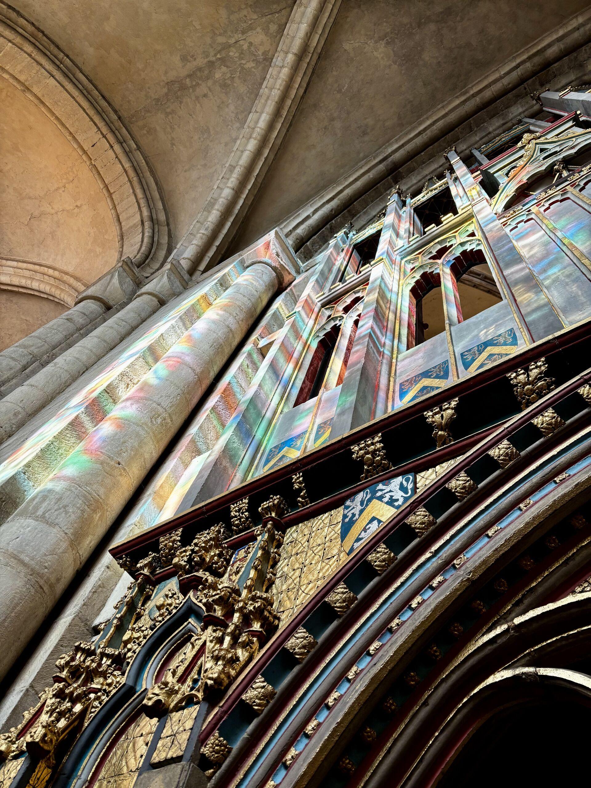 Rainbow light through stained glass on the gothic tracery of the high throne at Durham Cathedral