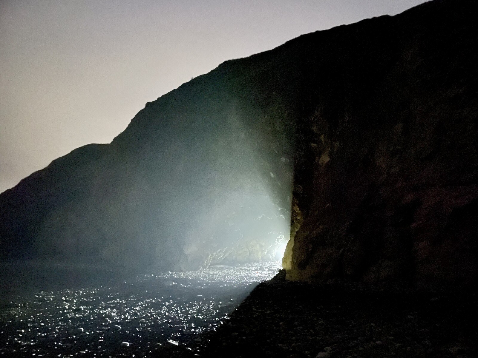 Light shining out of a cave in the dark at Blackhall Rocks