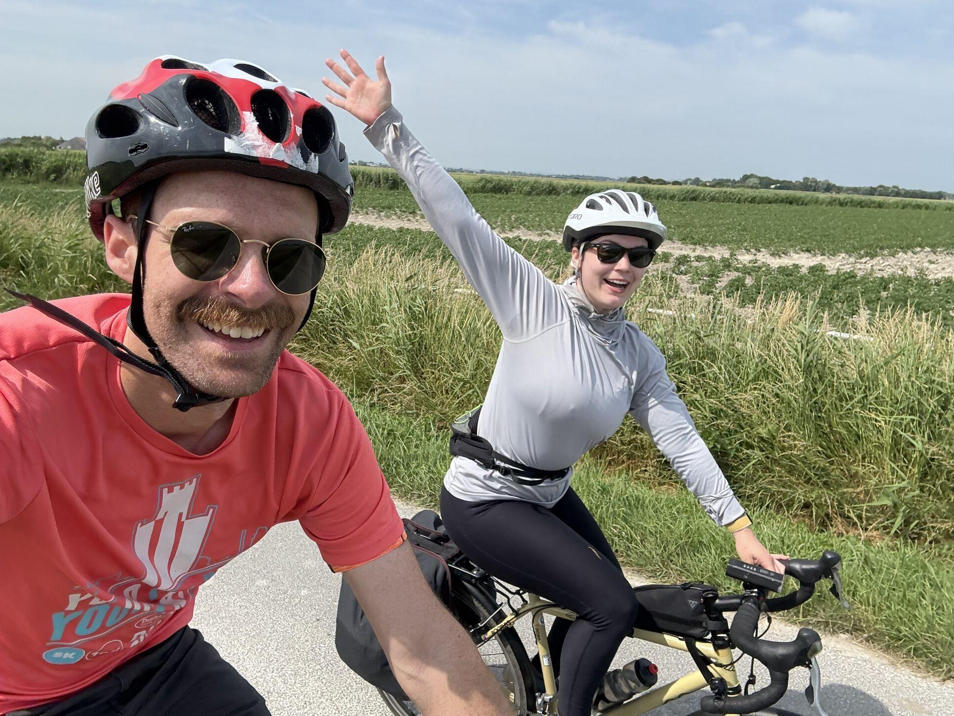 A selfie taken by one of two people on bicycles riding through a big crop field
