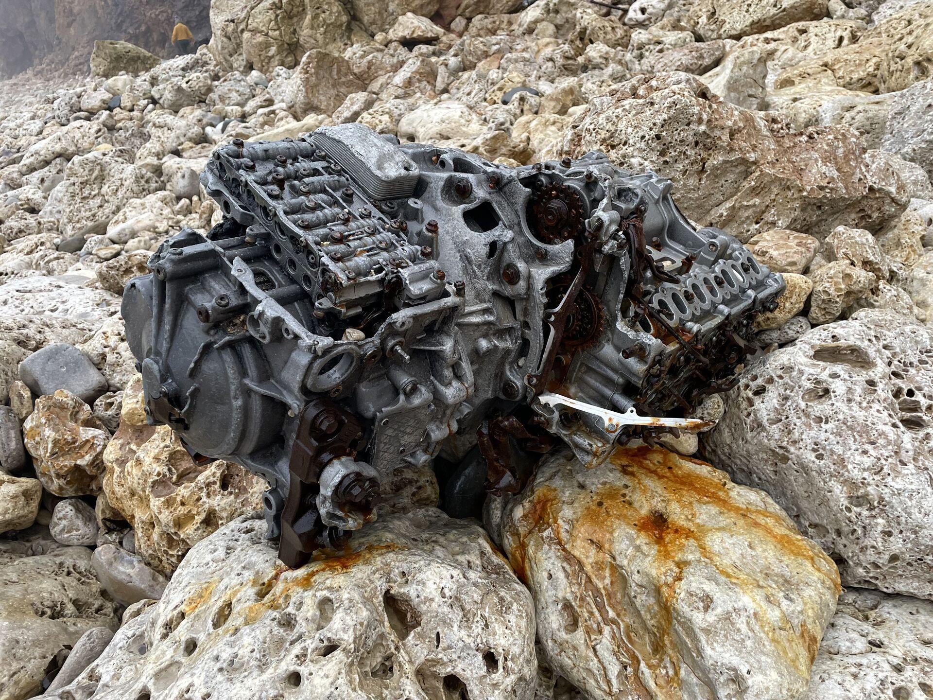 An aluminum engine block sitting on a heap of porous white stones