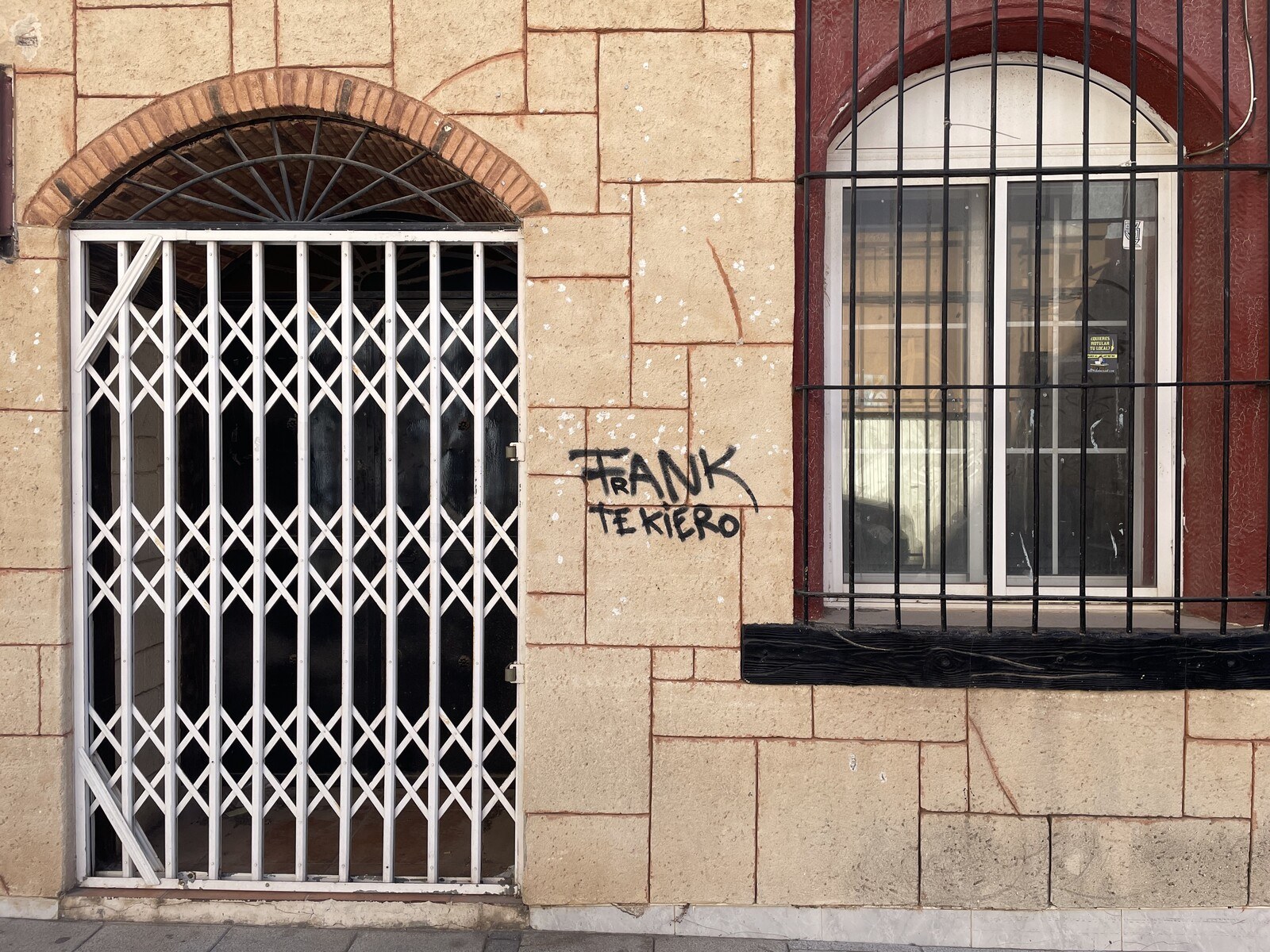 A graffiti on the side of a stone building reading "Frank te kiero"