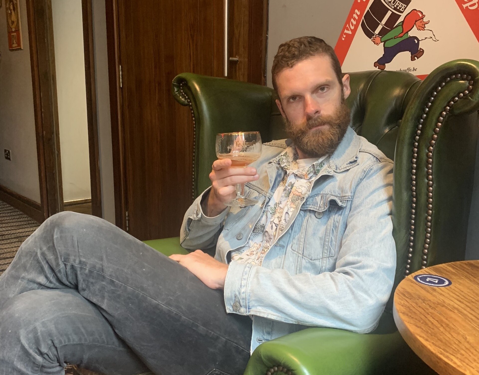 A picture of me with a half-empty coupe of Belgian ale, sitting in a fancy green leather armchair