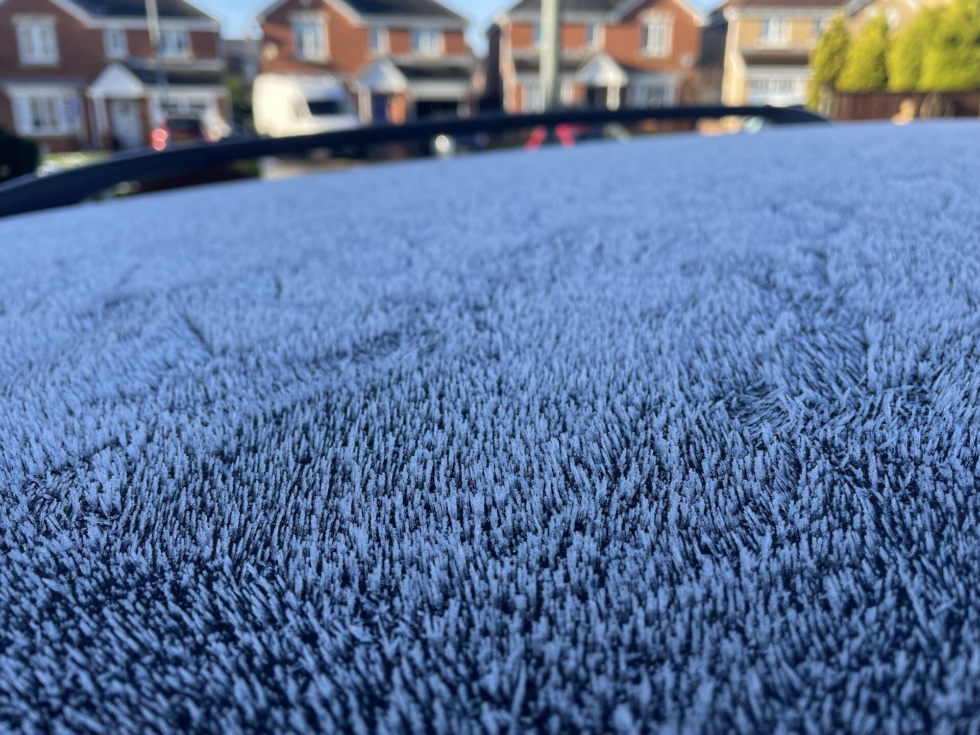 A close-up view of little frost stubble on the roof of a car, clearly in the wake of a chilly night