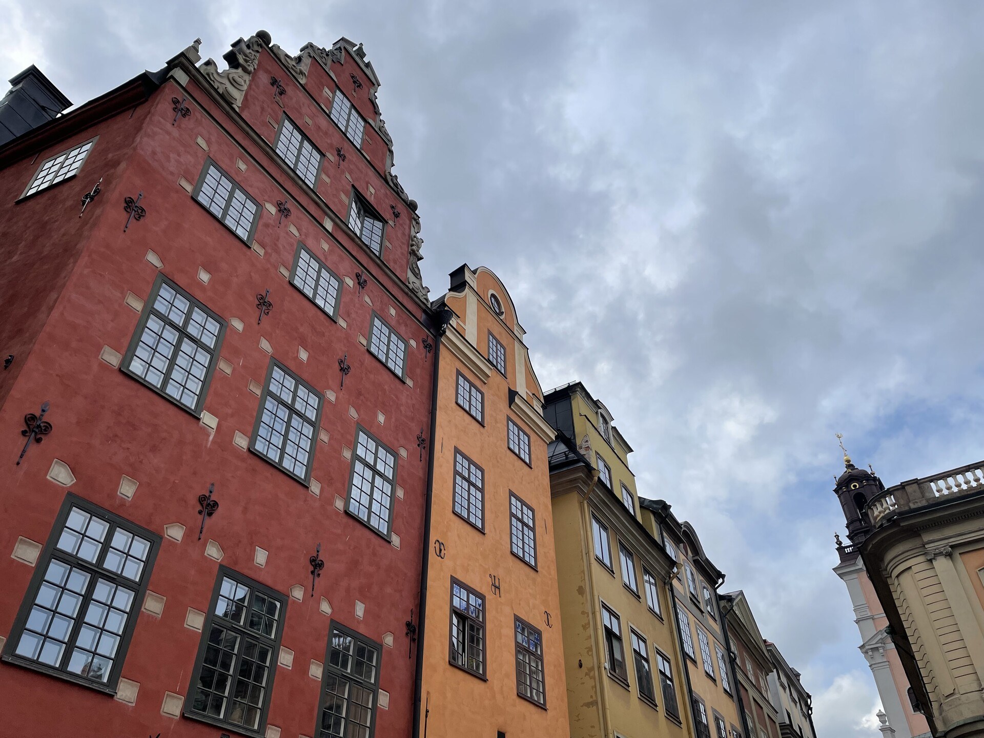 Looking up at the multicoloured facades of old terraced buildings in Gamla Stan, with an overcast sky beyond