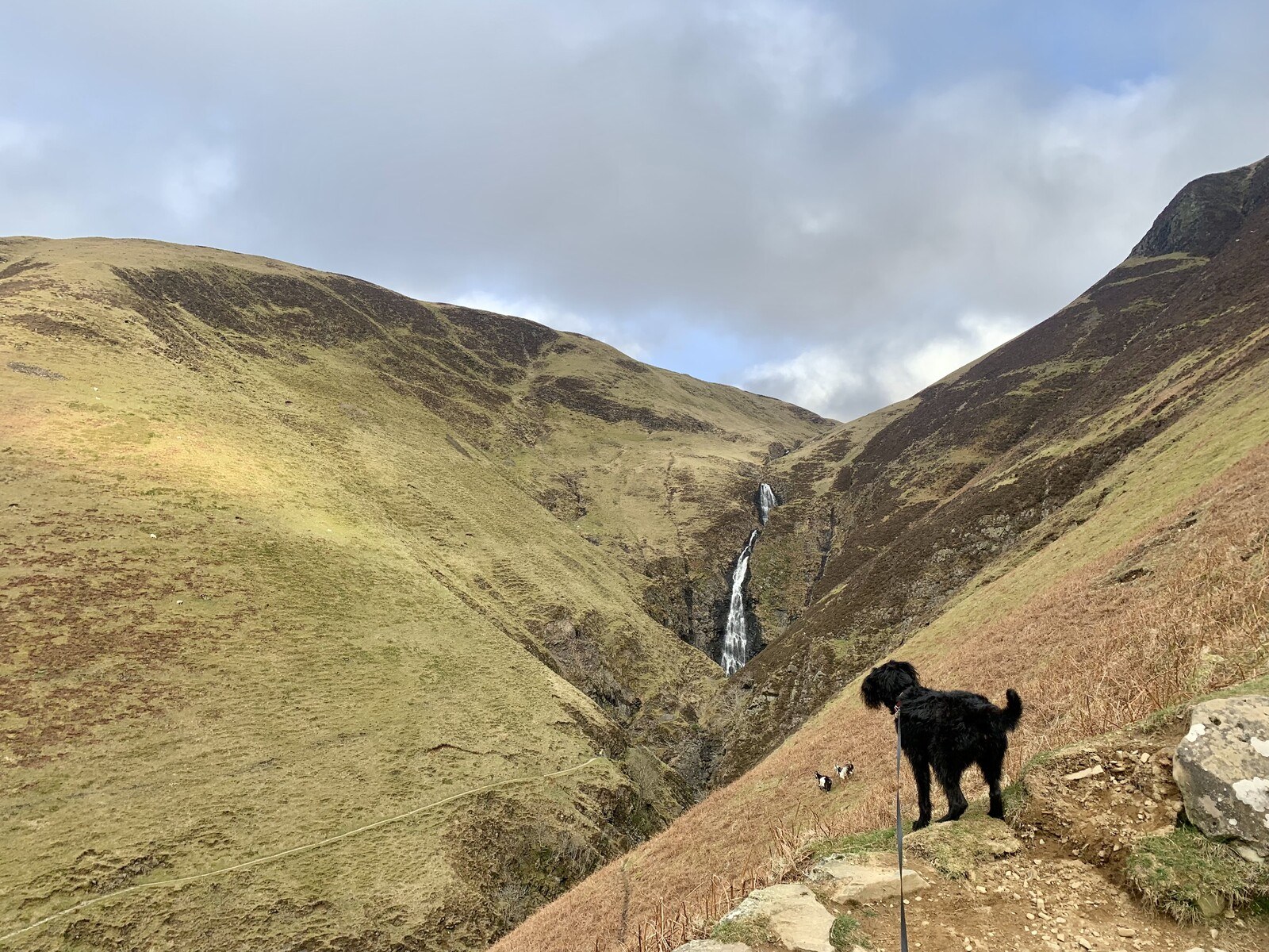 Ghyll overlooking a deep cleft between steep grassy hills with a waterfall at the top of the cleft
