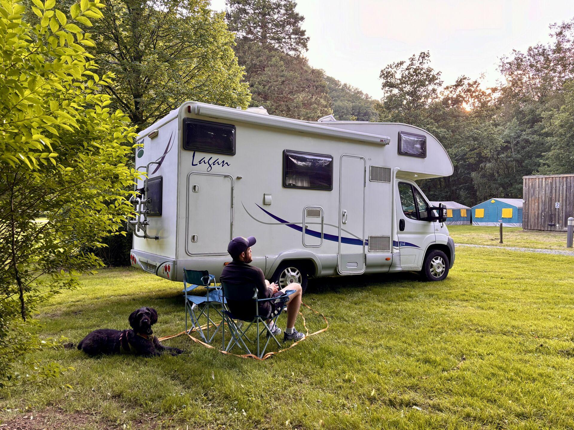 Me on a camp chair next to the campervan in the campsite, with Ghyll tied up in knots behind me.