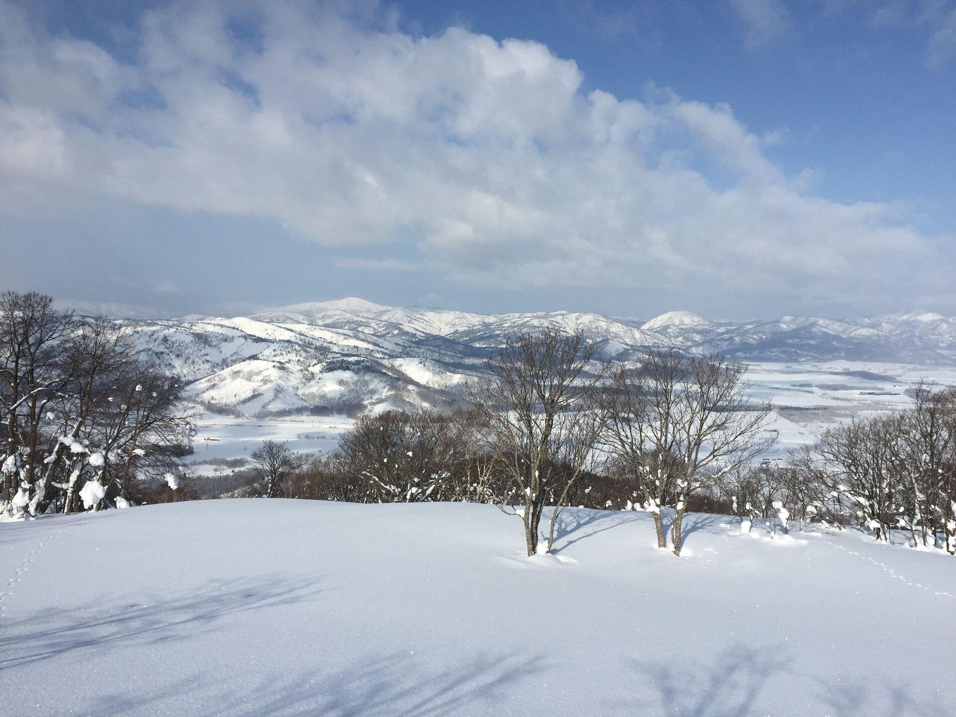 White, forested hills stretching off into an increasingly blue sky