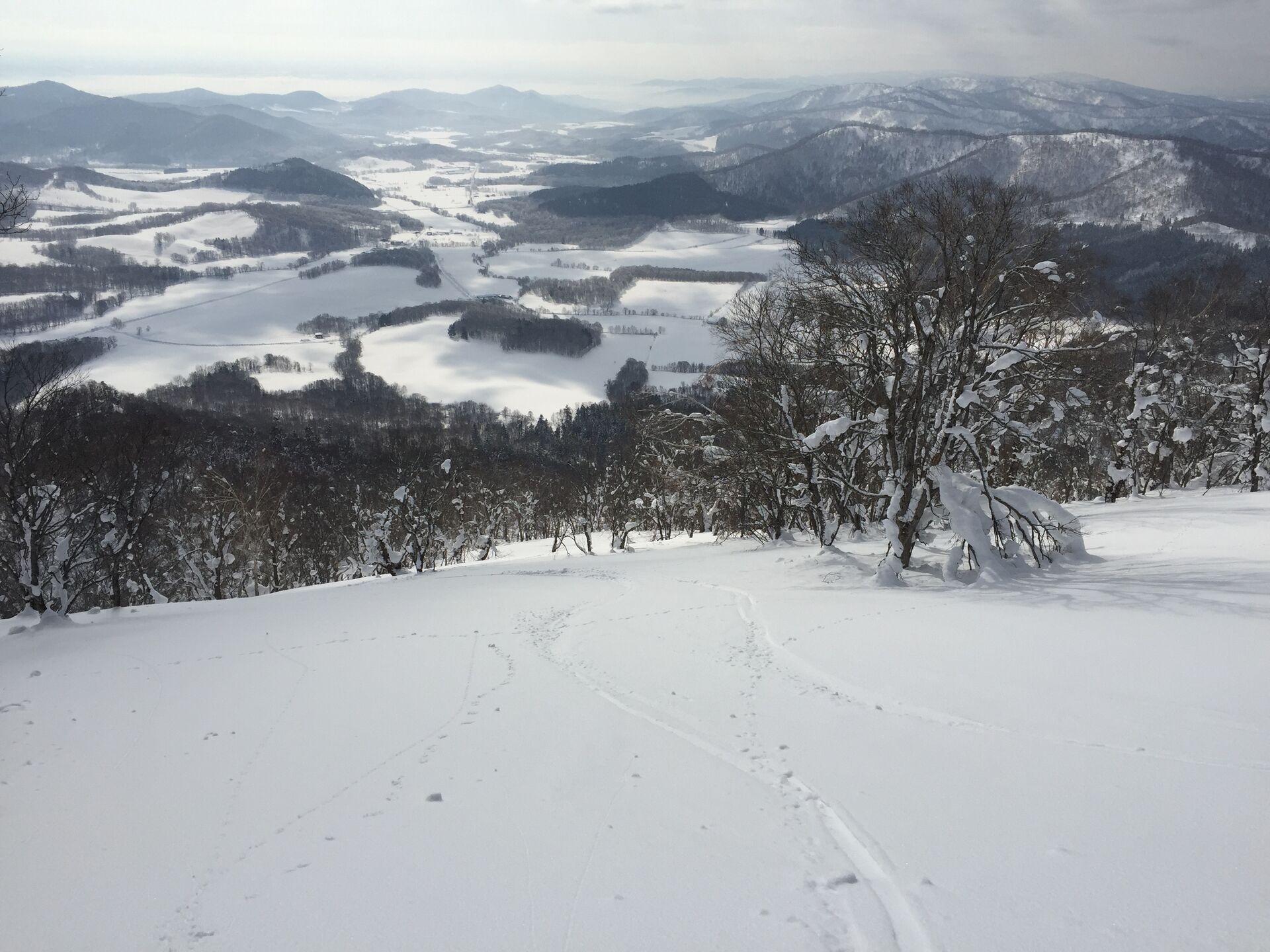 Looking down the snowy slopes to the fields below