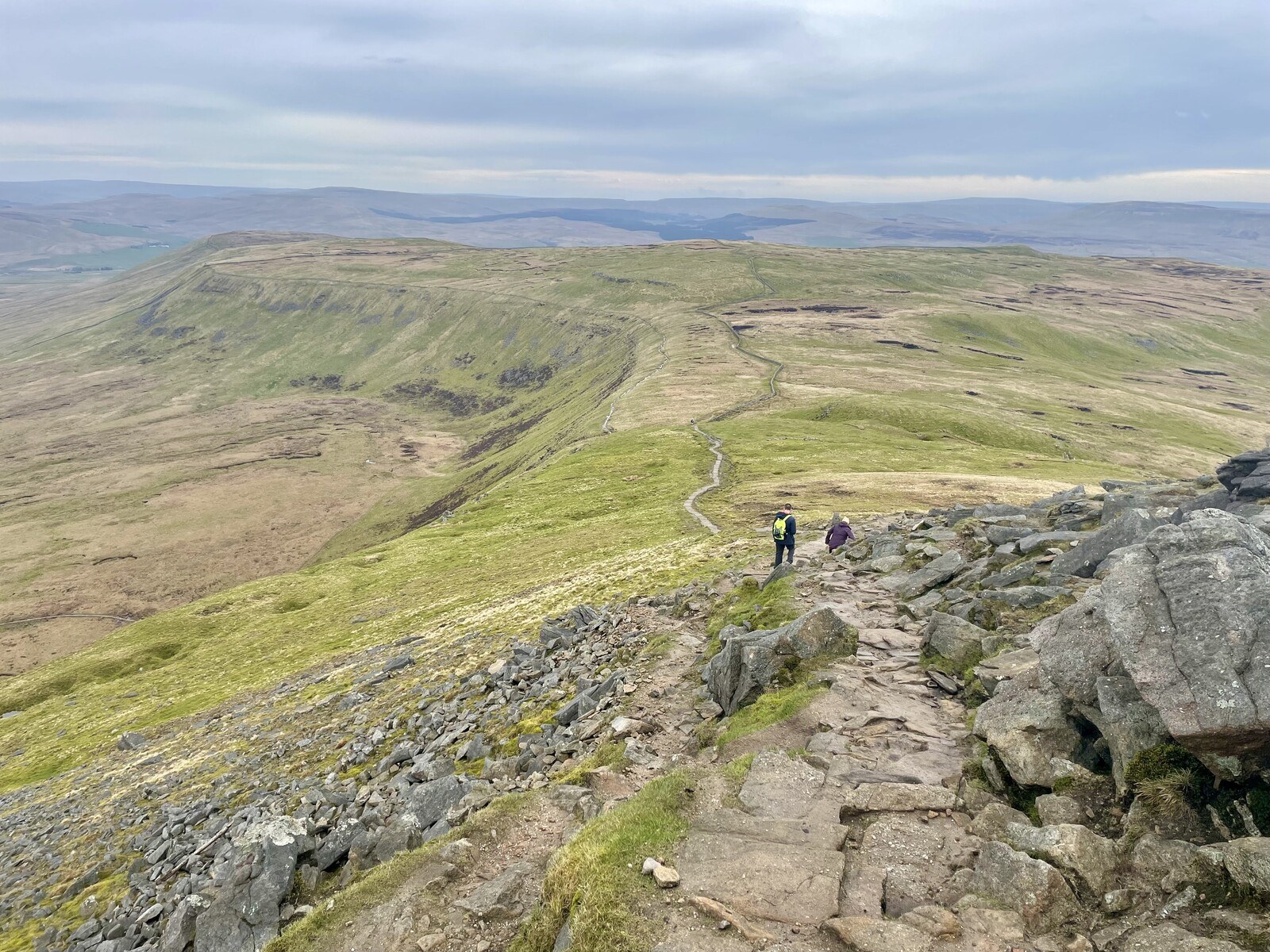 The stony trail leading down the side of Ingleborough, disappearing into a broad plateau in the distance and dropping off precipitously to the left