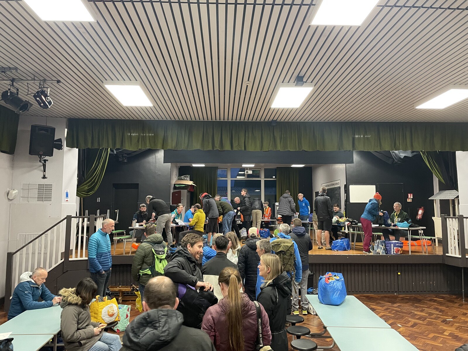 Runners waiting in the queue for kit check, up on the stage of the school hall.