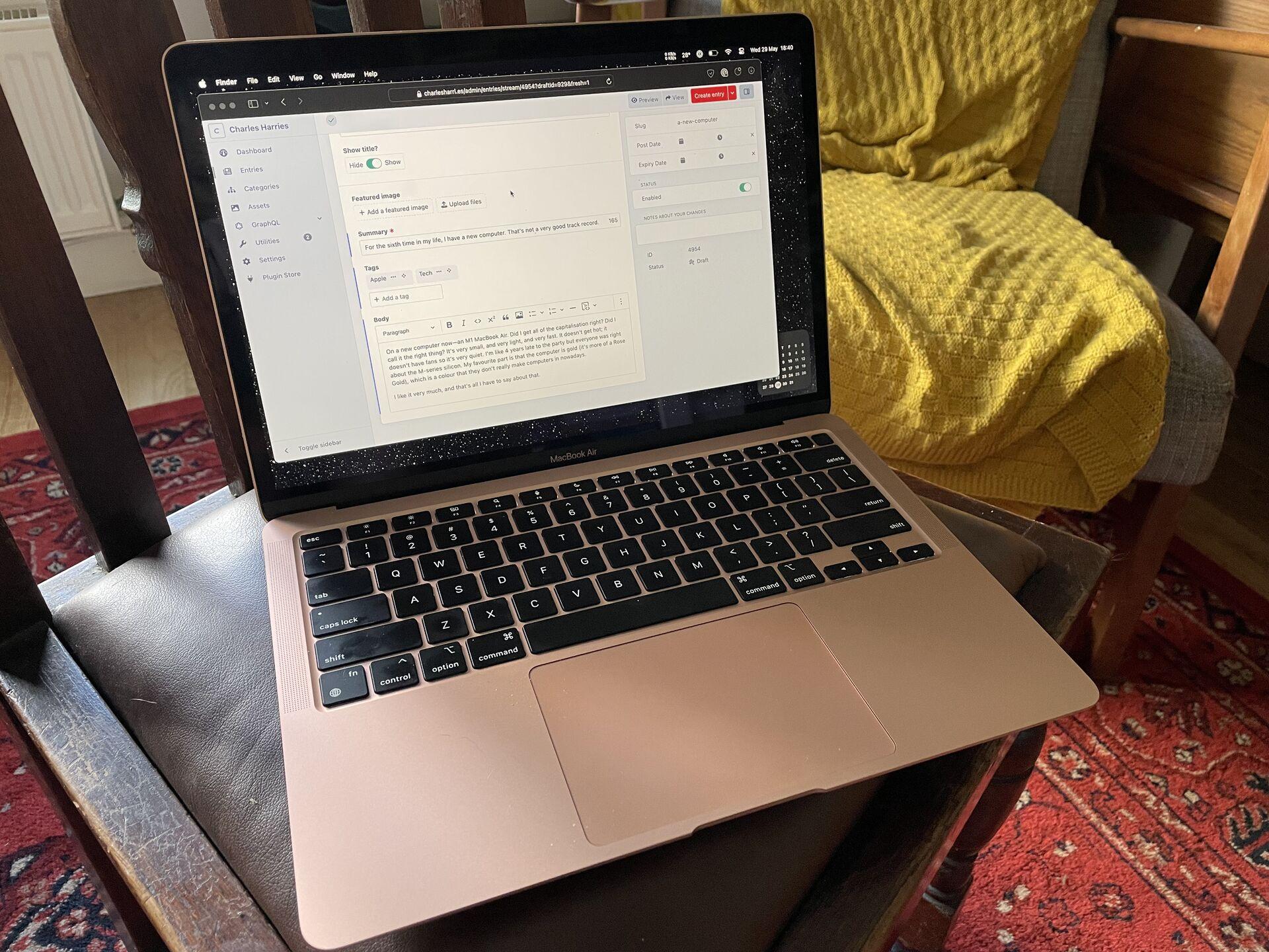 A gold MacBook Air on a dining chair, with the admin panel of this post open on the screen.