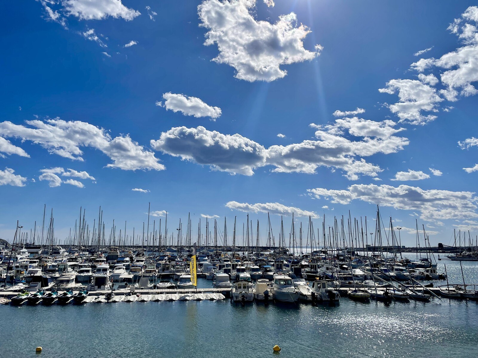 A marina full of sailboats under a lightly clouded sky