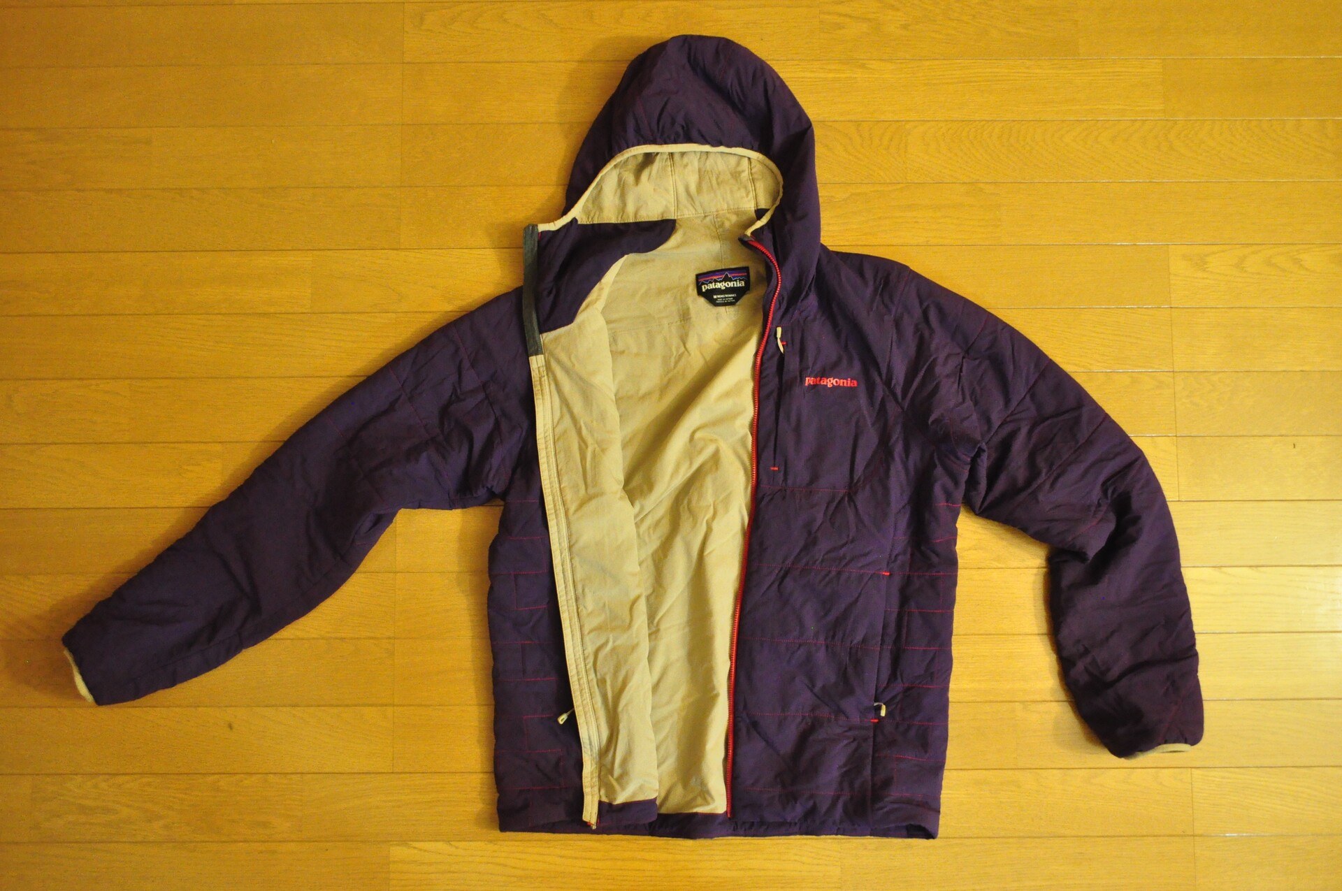 An overhead product shot of a lightweight purple insulating jacket