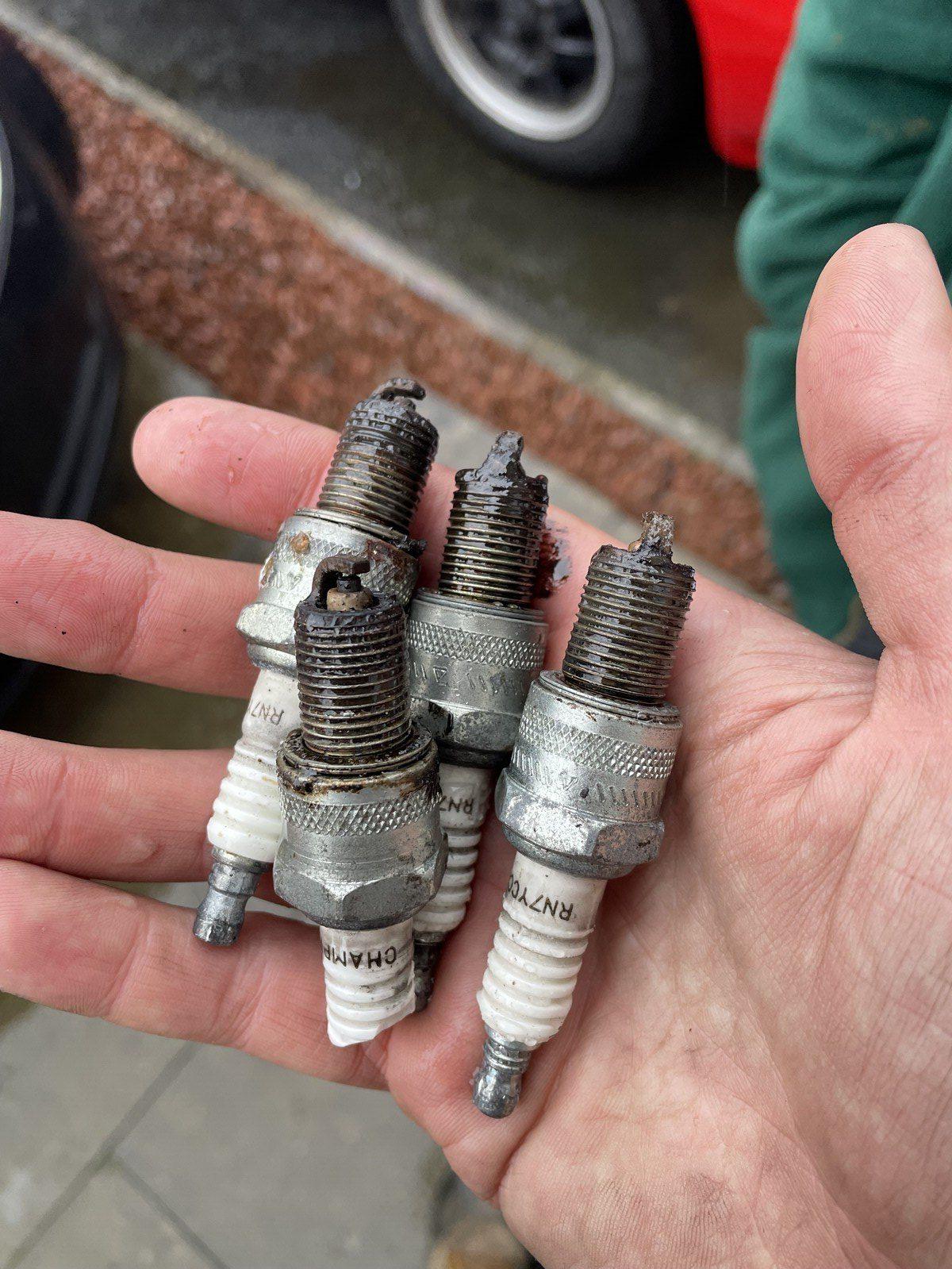 Holding a set of extremely gunky spark plugs, maybe with evidence that we'd flooded the engine at some point