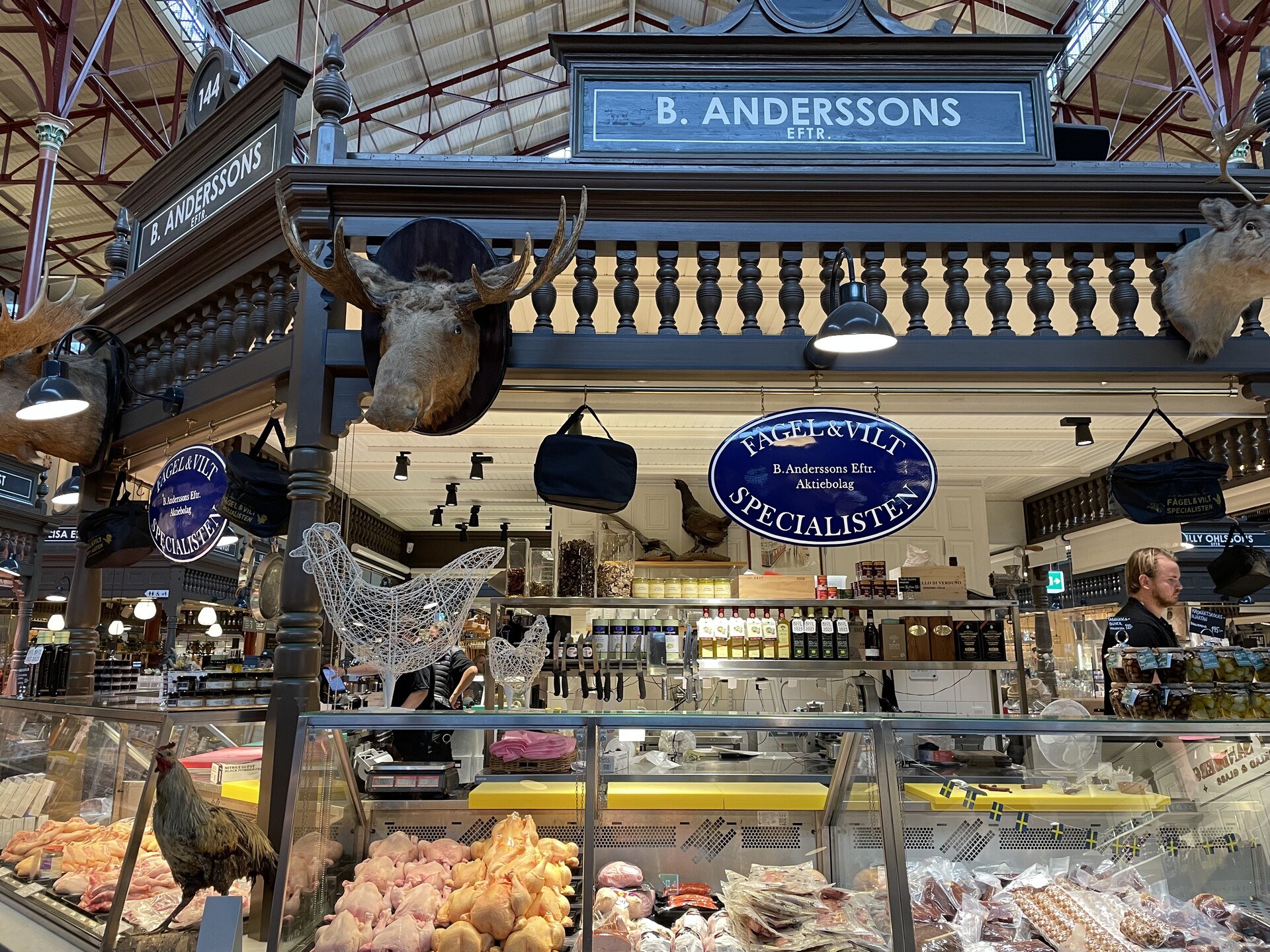 A meat stall labeled B. Anderssons with gratuitous (though arguably relevant) taxidermy mounted above the products