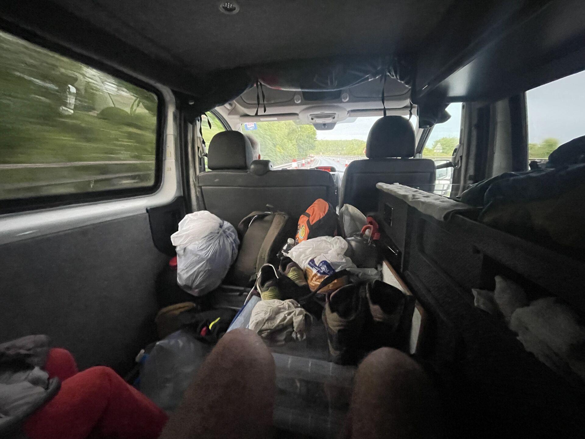 A blurry view from the rearmost row in a small van, with equipment lying all over the place inside