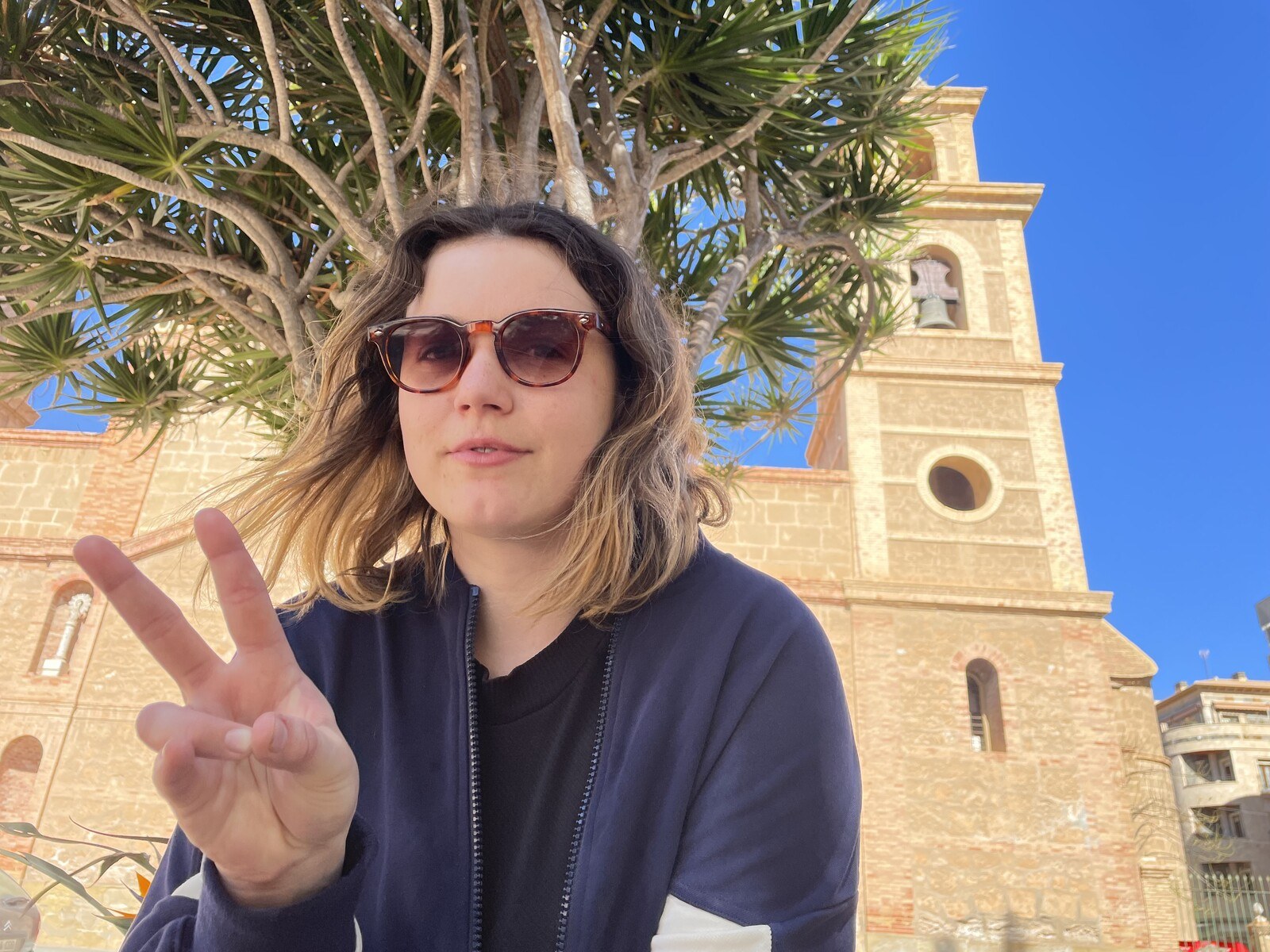 Sam flashing a peace sign in front of an old church in Torrevieja
