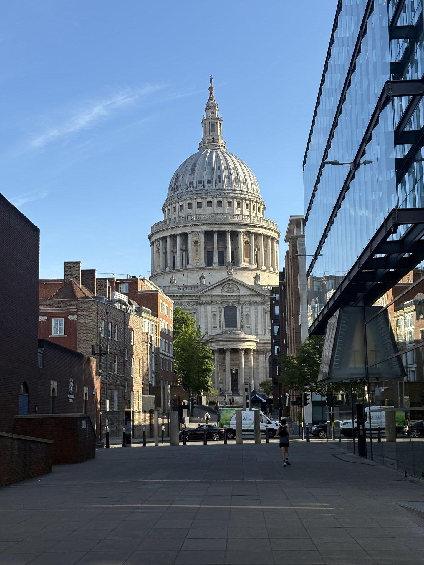 A view of the great white dome of St. Paul's Cathedral in London emerging between a row of Georgian buildings on one side and a massive steel-and-glass office block on the other