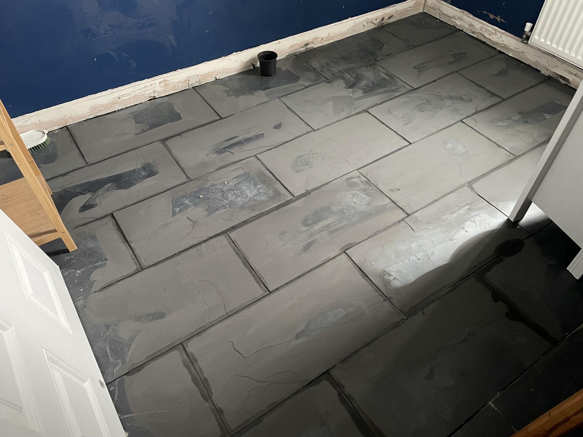 A tiled floor hazy with the sponged-down remains of grout