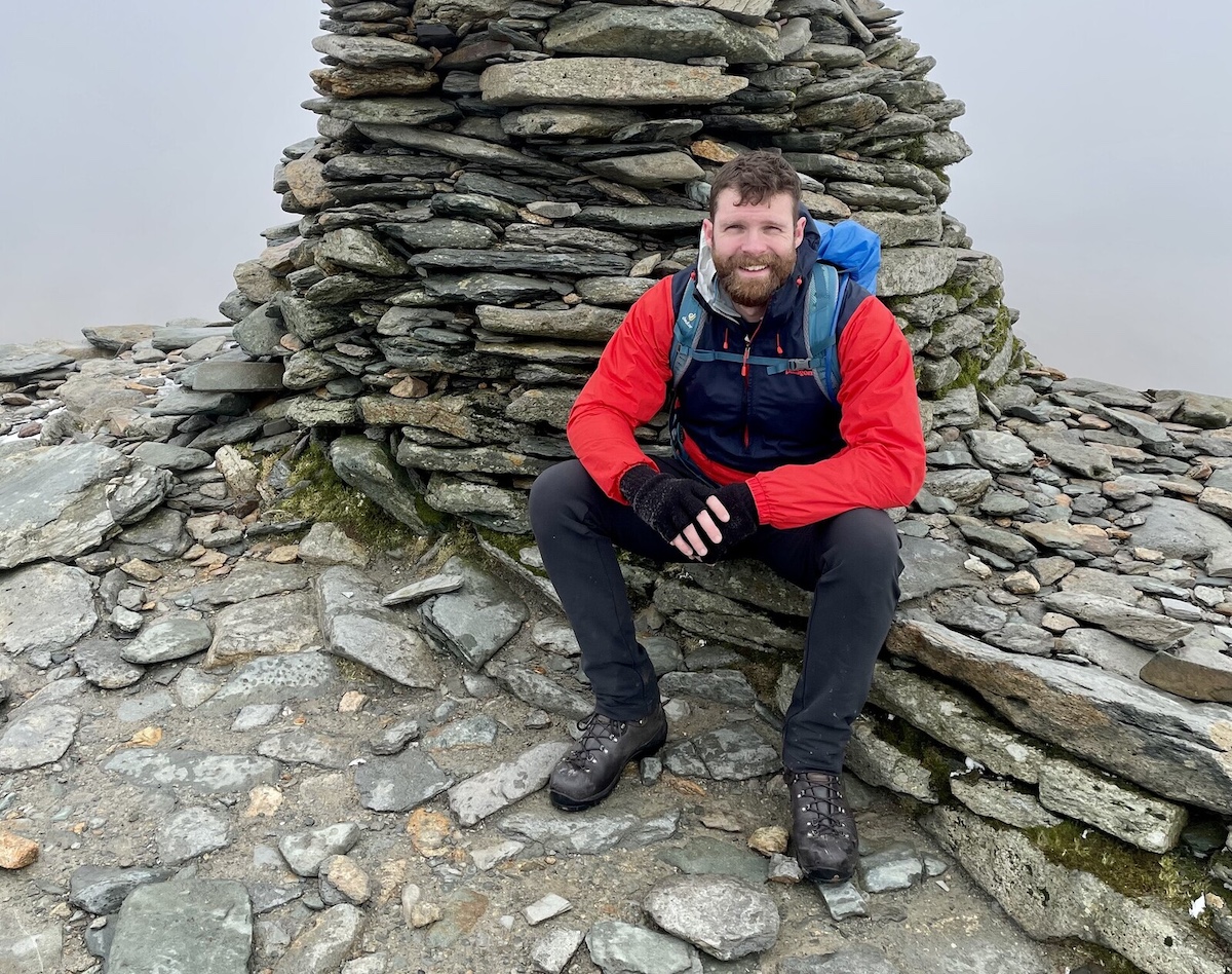 Me, sat next to a cairn on the summit of the Old Man of Coniston in the Lake District, in the United Kingdom.